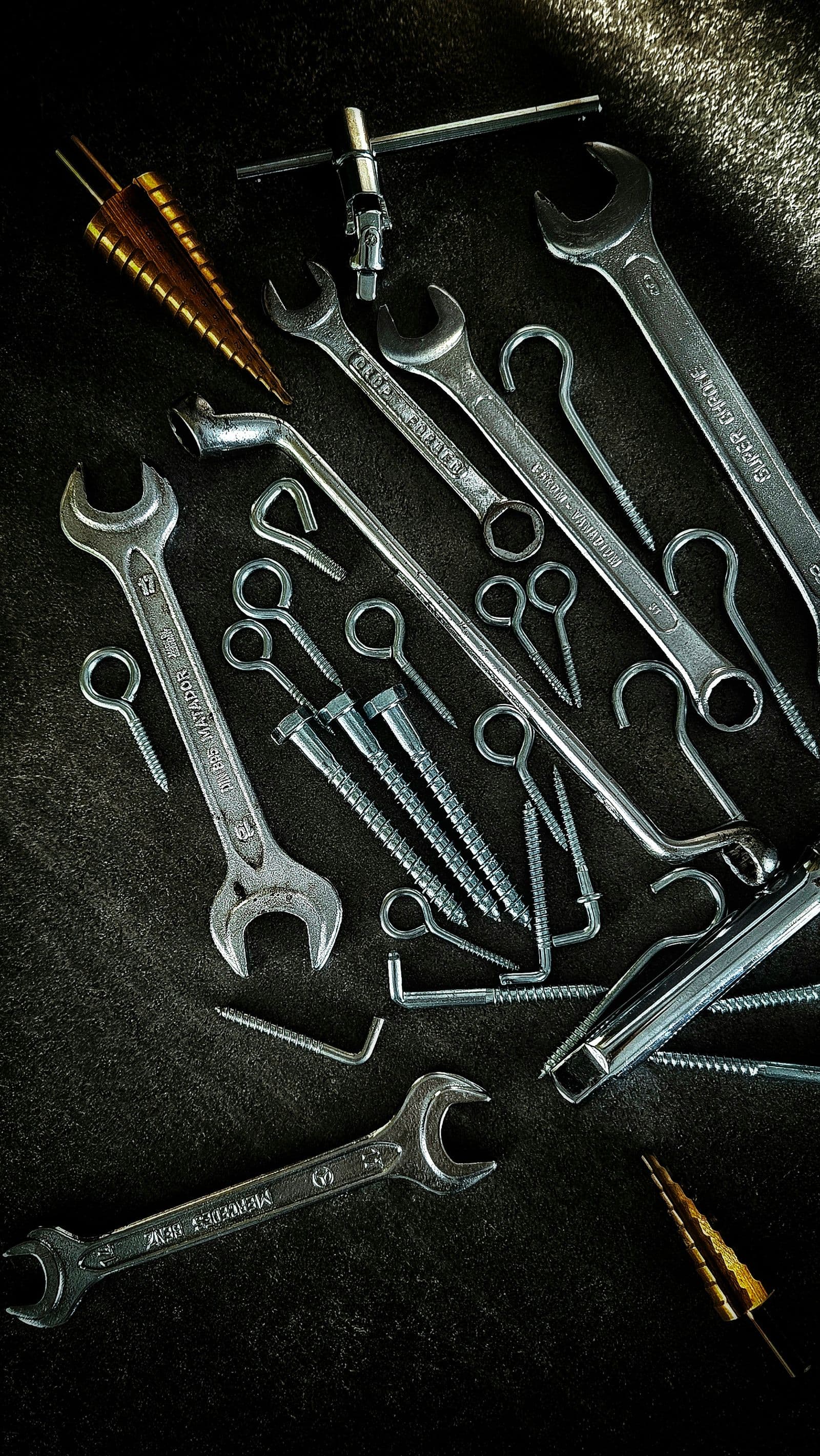 Wrenches and fasteners arranged on a dark workbench